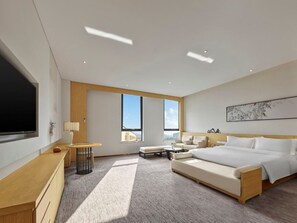 A modern hotel room with a large bed, a desk, a TV, and a window with a city view. - Garrya Xian Lintong (Xi'an)