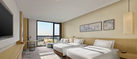 A modern hotel room with two beds, a large window, and a city view.