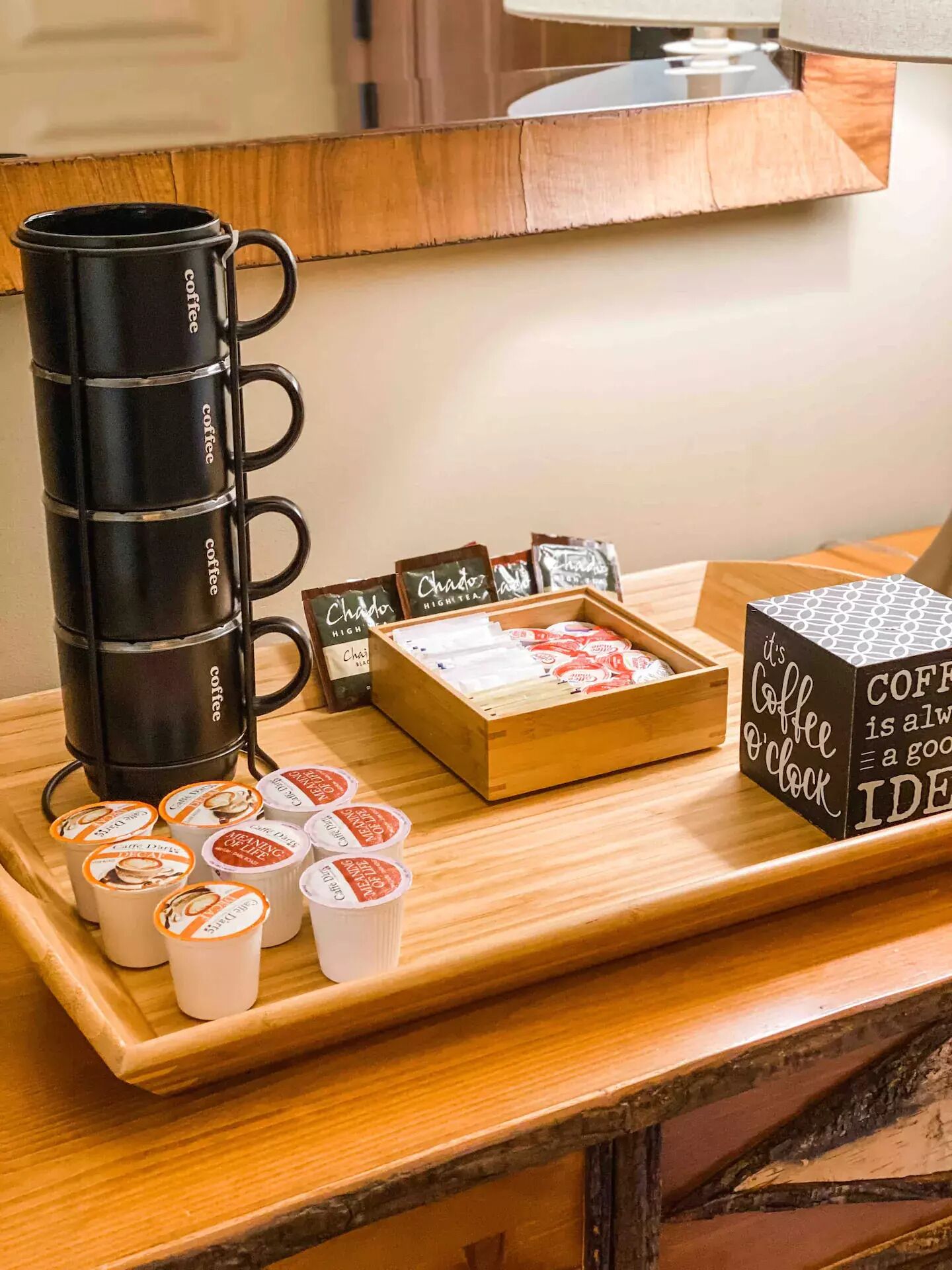 Eine Kaffeestation mit Kaffeemaschine, Teebeuteln und Kaffee-Kapseln auf einer Holztischplatte.