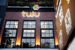 A building with a prominent 'tuju' sign above three large windows. - Tuju Arteri Pods by Zuzu (Jakarta)
