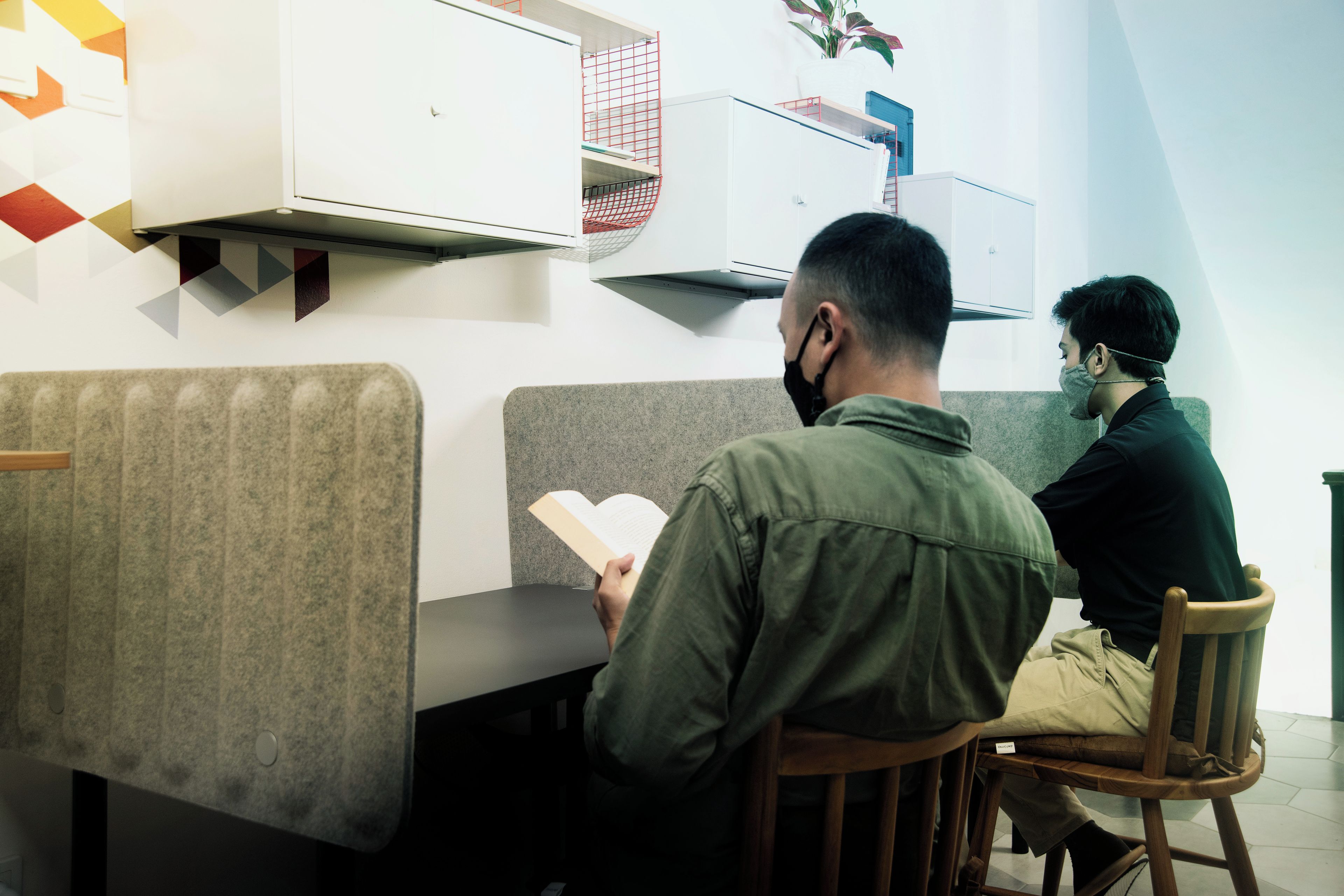 A person reading a book in a modern, well-lit room with a bench and a chair.