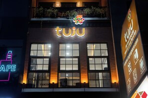 Un edificio con un llamativo letrero 'tuju' sobre la entrada.