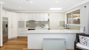 Una cocina moderna con armarios blancos, horno empotrado y una isla grande con fregadero.