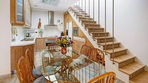 Eine moderne Küche mit Holzausstattung, einem Glastisch und einer Treppe mit gemusterten Stufen.