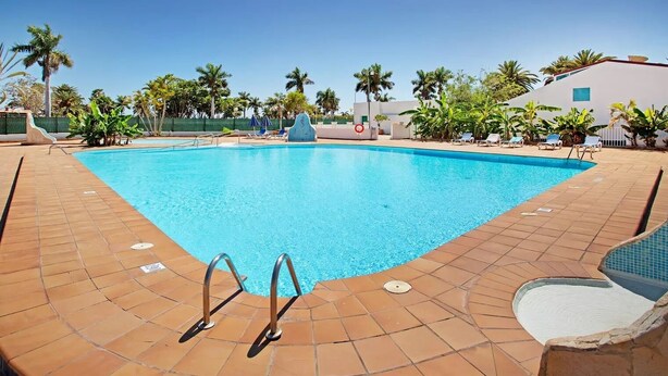 Ein rechteckiger Swimmingpool mit klarem, blauem Wasser, umgeben von einer gefliesten Liegefläche.