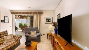 Ein Wohnzimmer mit einer Couch, einem Sessel, einem Couchtisch und einem Flachbildfernseher.
