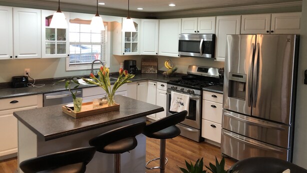 A modern kitchen with white cabinets, stainless steel appliances, and a central island with bar stools.
