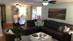 A living room with a sectional sofa, a coffee table, and a dining area with chairs and a table.