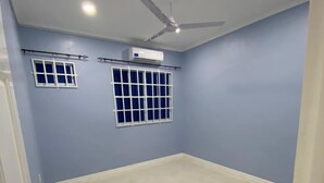A room with a tiled floor, a ceiling fan, recessed lighting, and two windows with curtains. - SINGH'S APARTMENT  (Georgetown)
