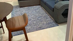 A living room with a grey sectional sofa, a small round table, and a blue patterned rug. - SINGH'S APARTMENT  (Georgetown)