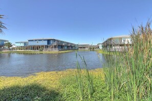 Una propiedad frente al lago, con un lago, un edificio azul con balcón y un edificio blanco con terraza.