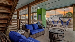 Un espace extérieur aménagé en terrasse, avec des meubles en osier, un hamac et un tonneau en bois.