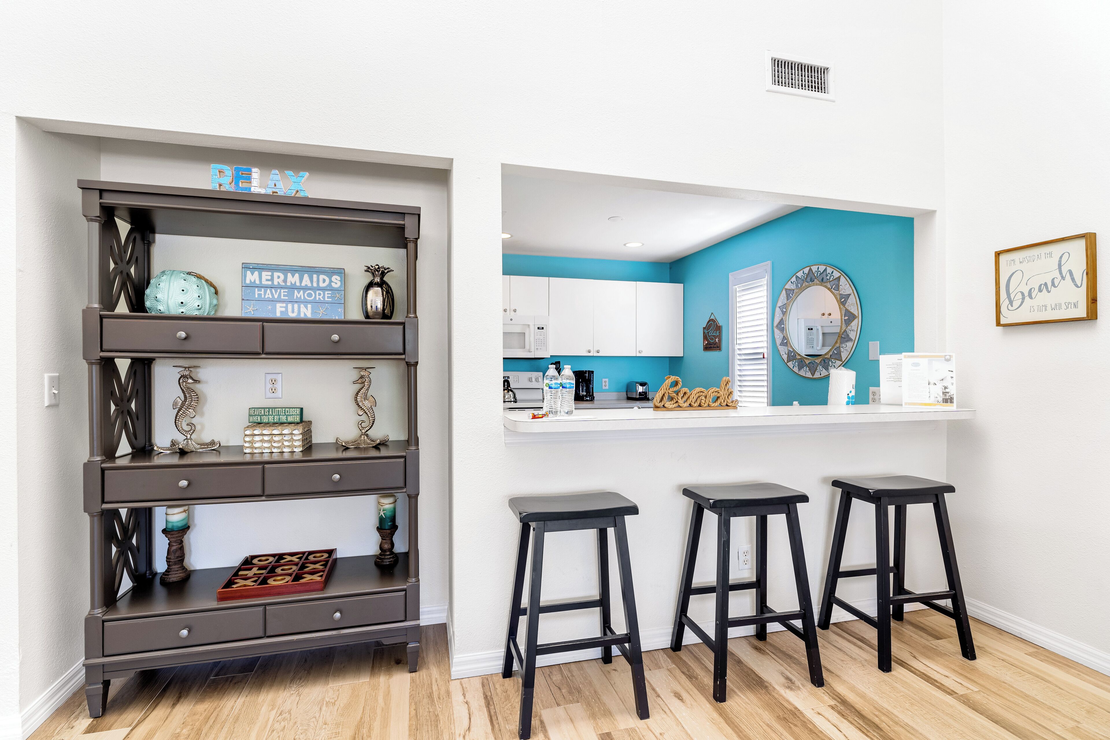A modern kitchen with white cabinets, a blue accent wall, and a bar area with stools.