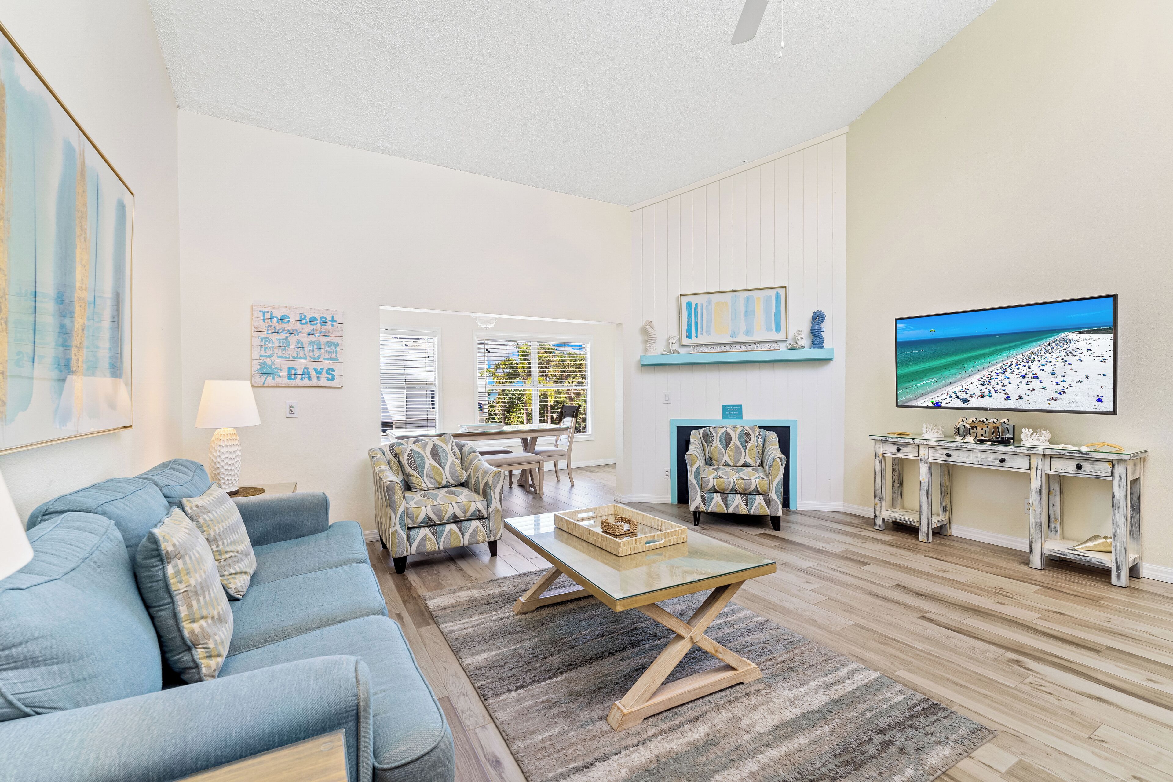 A living room with a blue sofa, patterned armchairs, a coffee table, a TV, and a fireplace.
