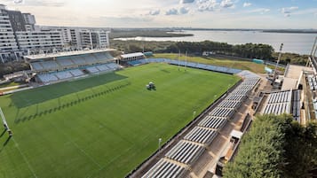 Stadium with a well-maintained grass field surrounded by semi-circular seating areas offering a clear view of the pitch.