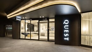 A modern hotel entrance with a 'QUEST' sign, glass doors, and a reception area. - Quest Woolooware Bay (Woolooware)