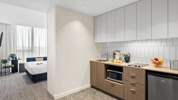 Una habitación de hotel moderna con kitchenette, una cama, un escritorio y vistas a la ciudad.