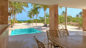 A poolside area with a view of the beach, palm trees, and ocean. - Casa Palmares - Yucatán Home Rentals (Telchac Puerto)