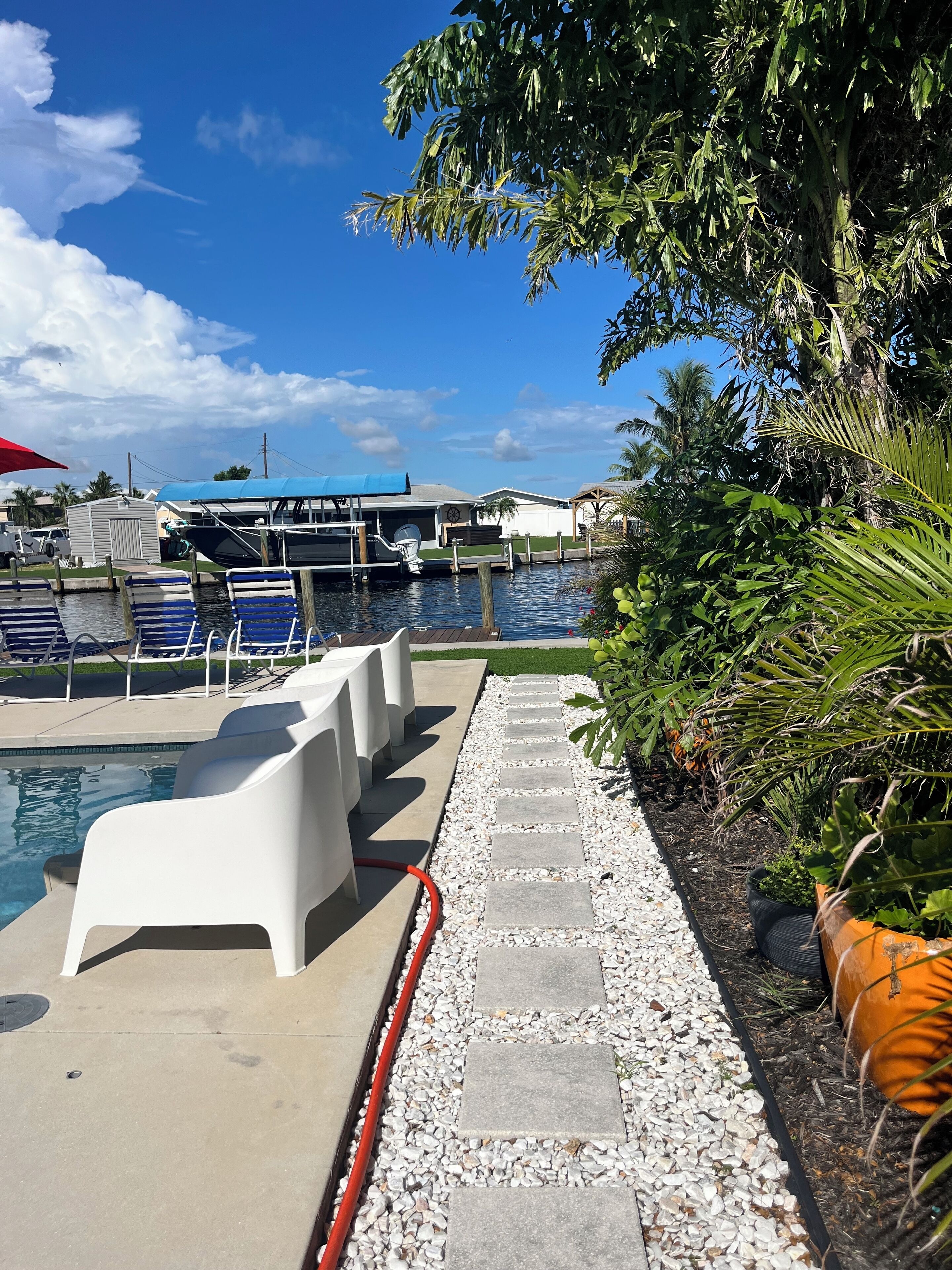 Un espace piscine avec des chaises longues, un sentier et une jetée avec des bateaux.
