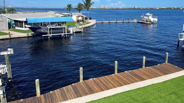 A marina with boats docked, a small building with a blue roof, and a grassy area in the foreground. - Waterfront oasis, sunsets, heated pool, hot tub, boat dock, near boat ramp (Bradenton)