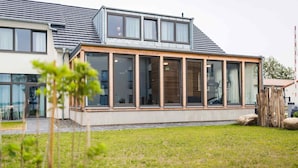 A modern house with large windows, a sloped roof, and a well-maintained lawn.