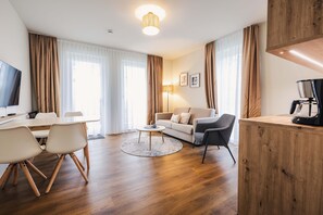 A modern living room with a sofa, chairs, a coffee table, and a TV. - Haus Zingst, Appartement 23 für bis zu 4 Personen. - Haus Zingst (Fuhlendorf)