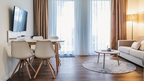 Uma sala de estar moderna com área de jantar, sofá e TV fixada na parede.