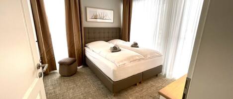 Una camera d'albergo con un letto, un comodino, una lampada e un quadro appeso al muro.