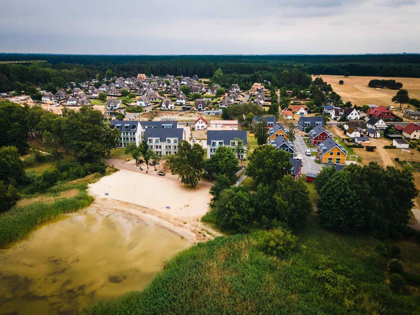 Luchtbeeld van een woonwijk met huizen, een strand en een rivier.