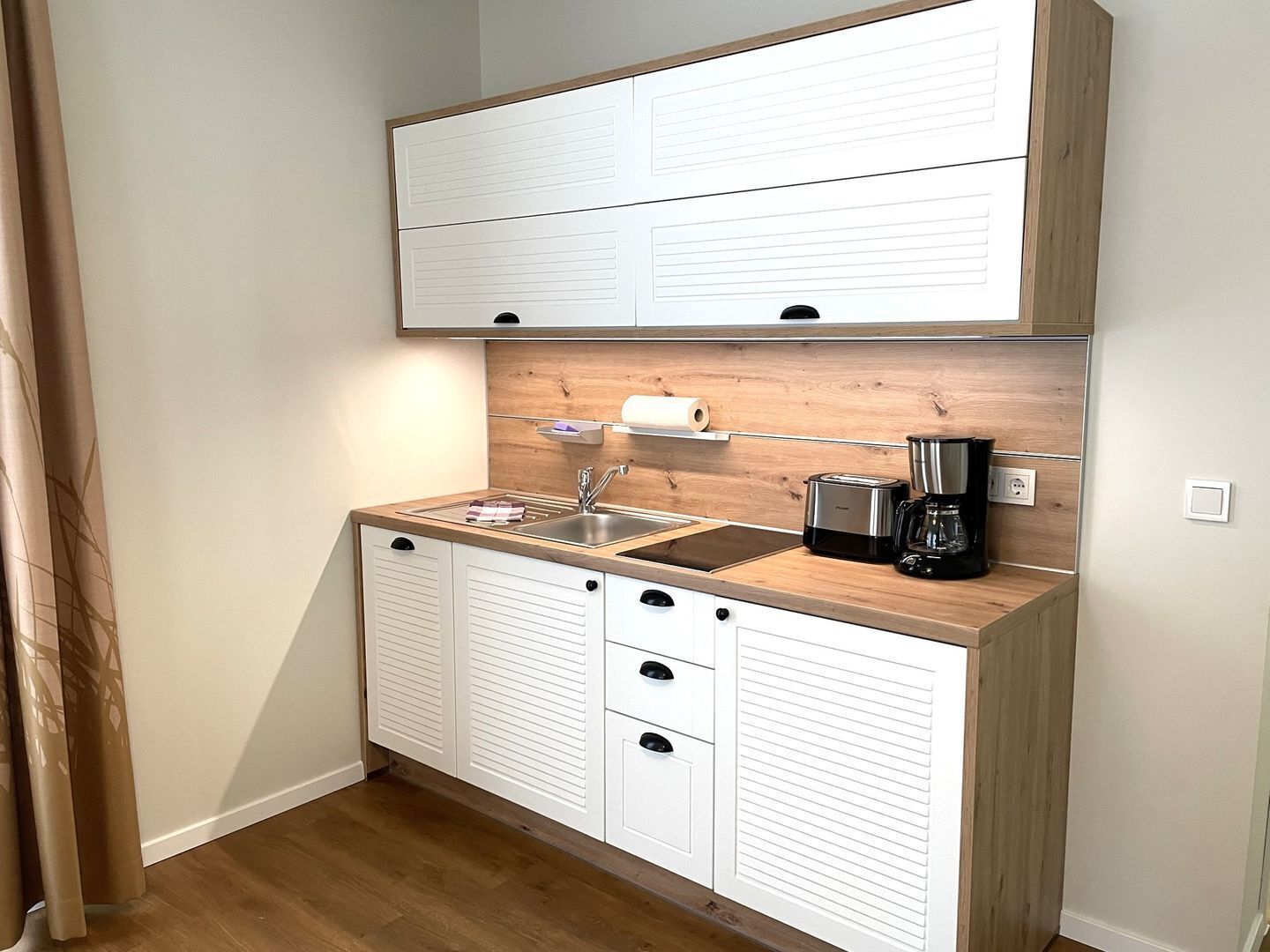 A compact kitchen with a wooden countertop, a sink, a toaster, and a coffee maker.