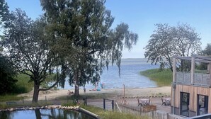 Näkymä järvelle, jossa on puinen terassi ja lasiovilla varustettu rakennus.