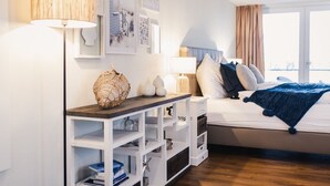 Un dormitorio moderno con cama, mesitas de noche, una consola y un ventanal grande.
