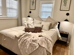 A neatly made bed with a white comforter, several pillows, a throw blanket, and a wicker basket. - Lodi Lounge: Private Spa + Walkable to Downtown (Lodi)