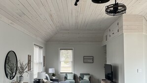 Amplia sala de estar con techo alto, vigas de madera y un comedor con mesa y sillas.