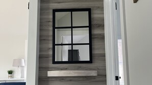 Un interior moderno con una pared de acento de madera, un espejo enmarcado y un sofá azul.