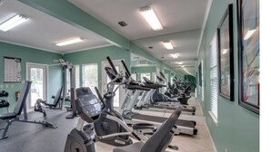 Un gimnasio con diversos equipos de ejercicio, incluyendo cintas de correr y máquinas de pesas, y una pared con un tablón de anuncios.