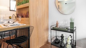 Un espace repas moderne avec une table en bois, des chaises en fil de fer noir et une petite table d’appoint en métal noir agrémentée d’objets décoratifs.