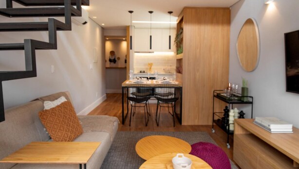 Un appartement moderne doté d’une chambre en mezzanine, d’un coin repas et d’un espace de vie comprenant un canapé et une table basse.