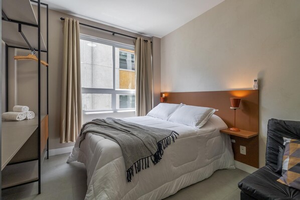 A hotel room with a bed, a bedside table with a lamp, a wardrobe, and a window with curtains. - Av0811 Studio Avanhandava (S ão Paulo)