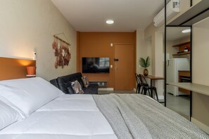 A hotel room with a bed, a TV, a desk, and a kitchenette. - Av0811 Studio Avanhandava (São Paulo)