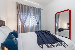 Camera d'albergo moderna con un letto, un comodino, uno specchio e una finestra con tende.