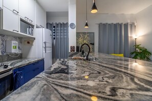 A modern kitchen with a marble countertop, built-in appliances, and pendant lighting. - Leo166-4 in S o Paulo (São Paulo)