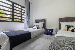 Una camera d'albergo con due letti, una finestra con persiane e vista sugli edifici.