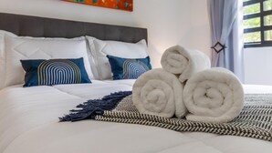 A neatly made bed with rolled white towels, a patterned throw blanket, and decorative pillows. - Leo166-4 in S o Paulo (São Paulo)