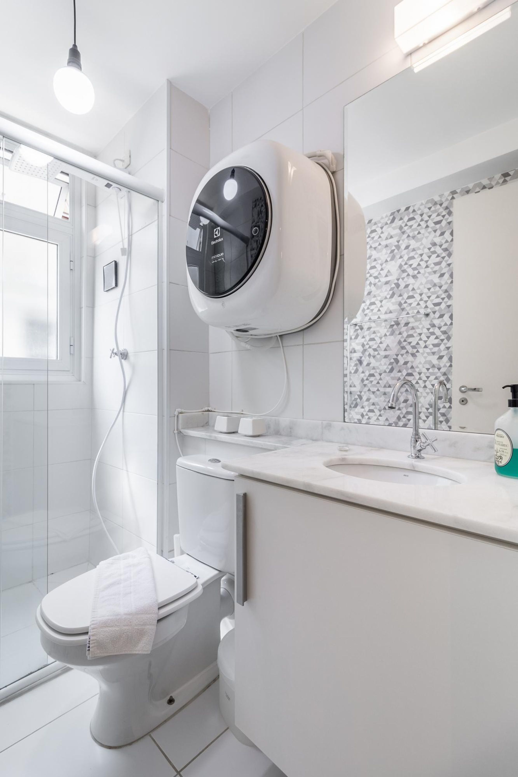 A modern bathroom with a toilet, a shower, a sink, and a mirror.