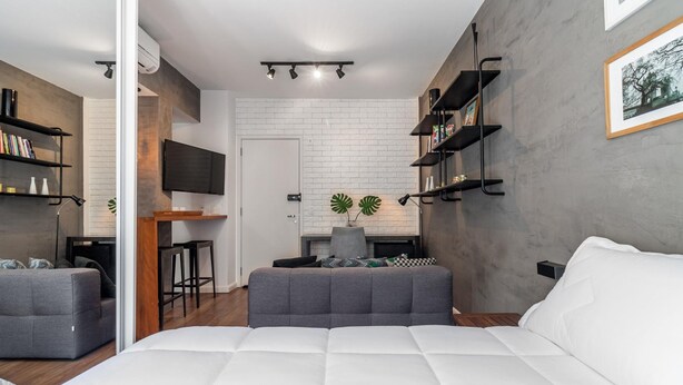Ein modernes Schlafzimmer mit einem großen Bett, grauen Sofas, einem Fernseher und einem Kamin.