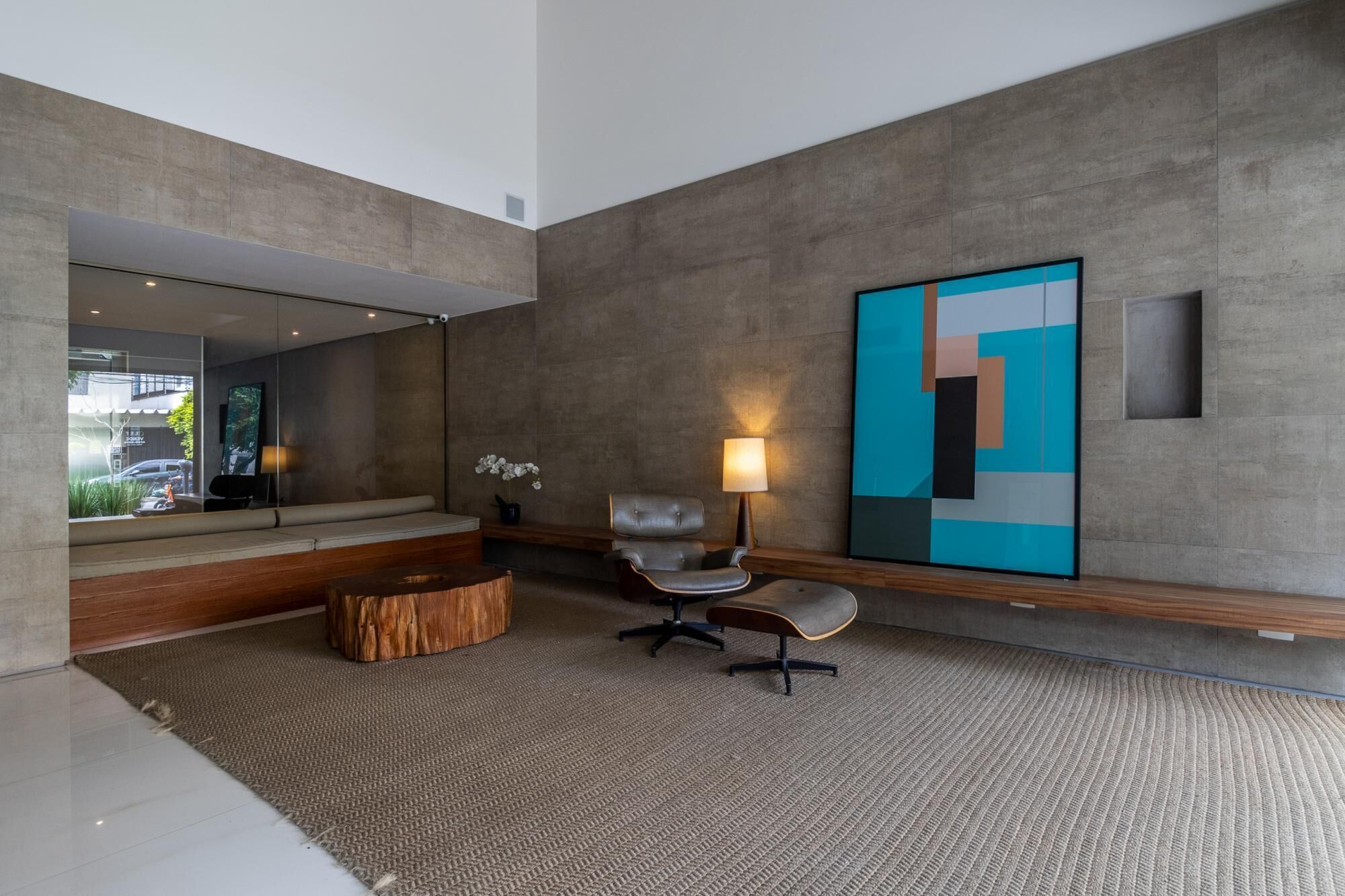 Un interno moderno con un grande quadro astratto, un'area salotto con divano e poltrone, e un'ampia finestra che si affaccia su una strada.