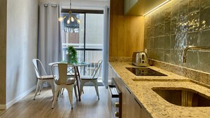 Een moderne keuken met een ingebouwde kookplaat, een spoelbak en een eethoek met stoelen en een tafel.