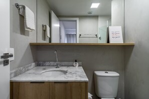 A bathroom with a marble sink, a toilet, and a shelf with a sign. - Sa1342-512 in S o Paulo (São Paulo)