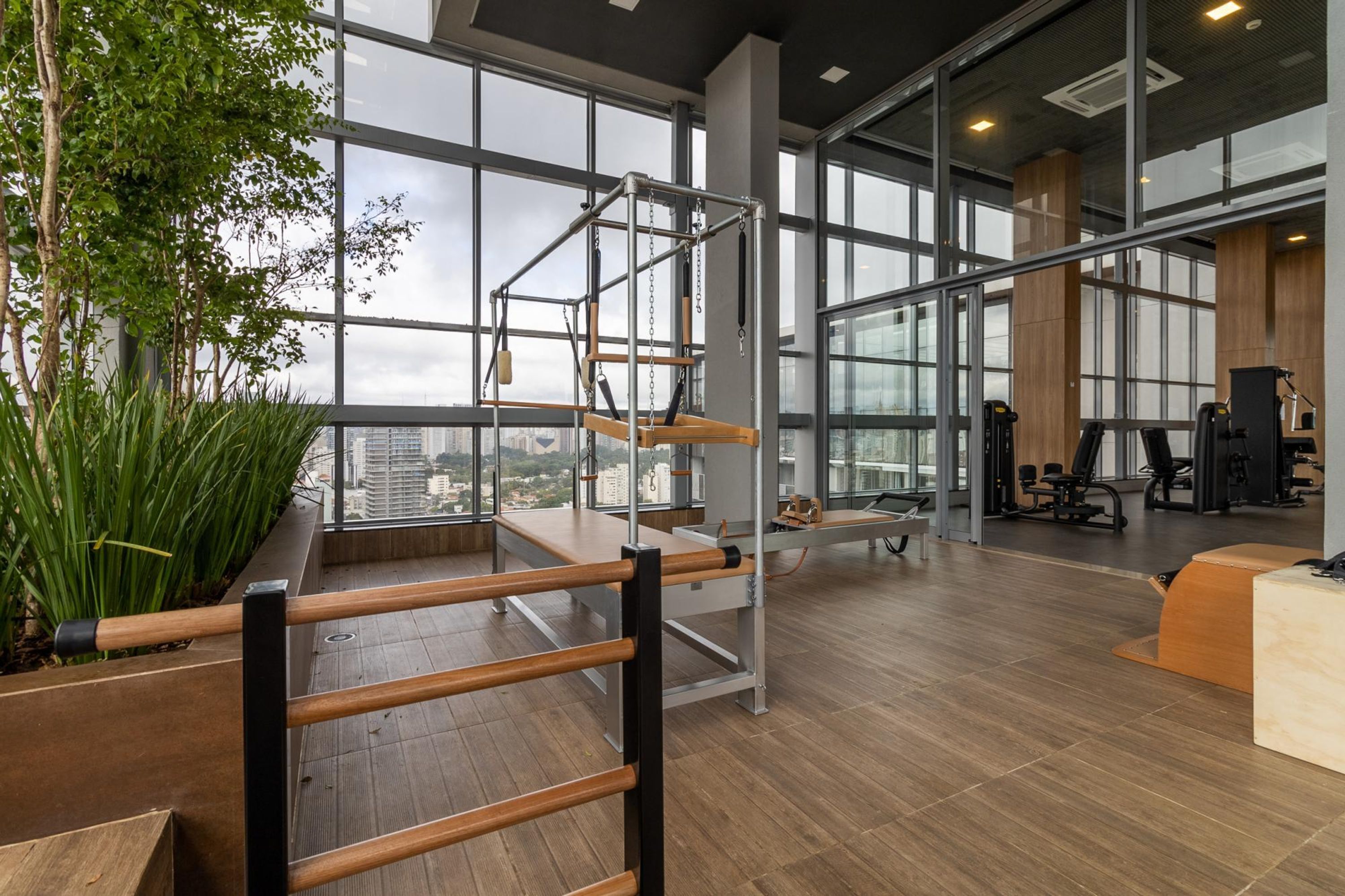 Une salle de sport équipée de matériel d’exercice, dotée de grandes fenêtres et offrant une vue sur la ville.